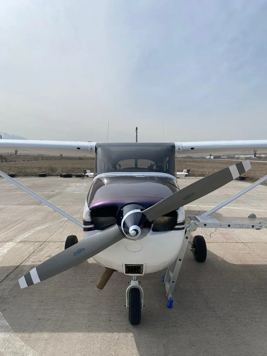 Front view of a small Cessna aircraft parked on the airfield tarmac near Almaty